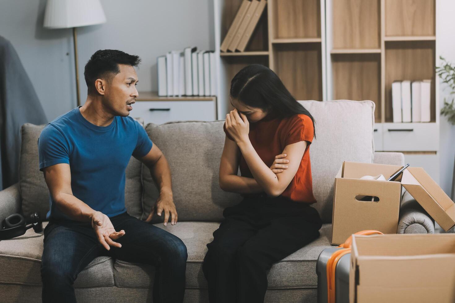 Family couple ignoring each other after a quarrel. Two people turn away and don't talk to each other. Angry young man and woman sitting back to back, with arms crossed on the sofa in the living room photo