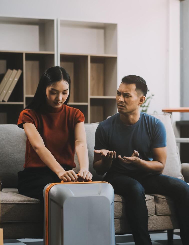Family couple ignoring each other after a quarrel. Two people turn away and don't talk to each other. Angry young man and woman sitting back to back, with arms crossed on the sofa in the living room photo