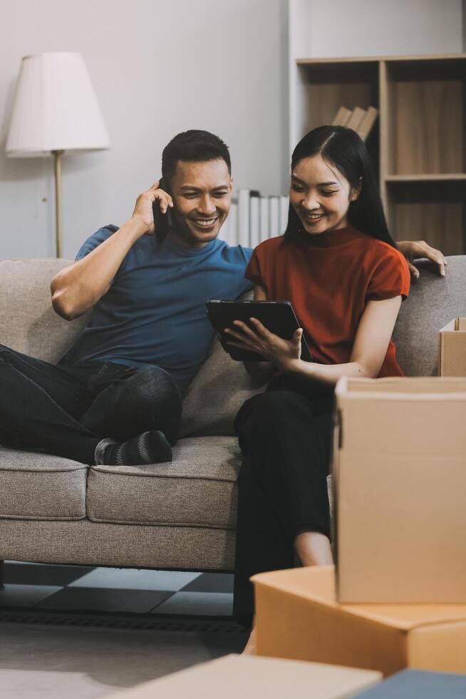Happy excited, smiling asian young couple love using tablet pc, great deal or business success, received or getting cash back, tax refund, good news by mail while sitting on floor at home. photo