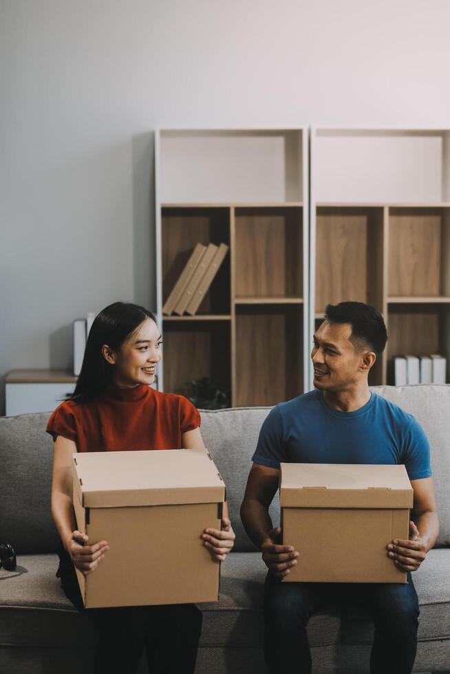 joven Pareja con grande cajas Moviente dentro un nuevo casa, nuevo Departamento para pareja, joven hombre y mujer Ayudar a levantar cajas y organizar cosas para el nuevo hogar, Moviente casa. foto