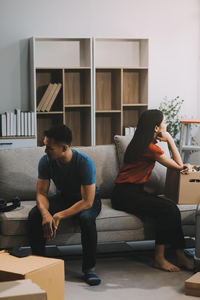 Family couple ignoring each other after a quarrel. Two people turn away and don't talk to each other. Angry young man and woman sitting back to back, with arms crossed on the sofa in the living room photo