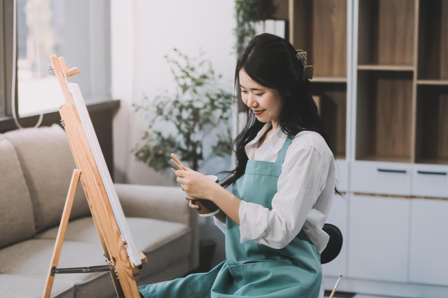 Pretty talented female painter painting on easel, making colorful sketches, creating marine landscape. Beautiful female artist painting with watercolor paints. Creativity and imagination concept photo