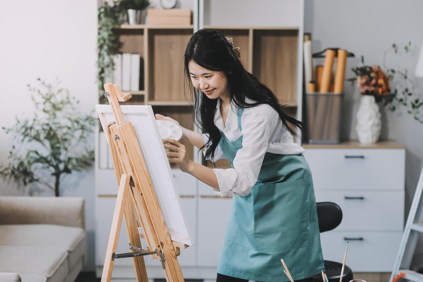 Pretty talented female painter painting on easel, making colorful sketches, creating marine landscape. Beautiful female artist painting with watercolor paints. Creativity and imagination concept photo