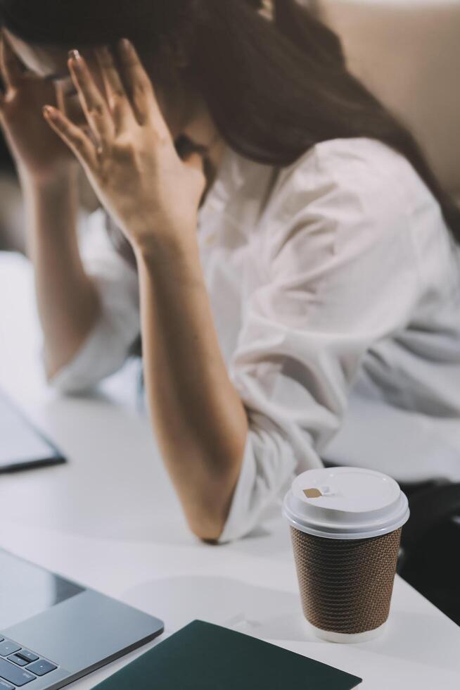 Asian women are stressed while working on laptop, Tired asian businesswoman with headache at office, feeling sick at work, copy space photo