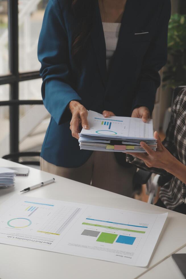 Group of confident business people point to graphs and charts to analyze market data, balance sheet, account, net profit to plan new sales strategies to increase production capacity. photo