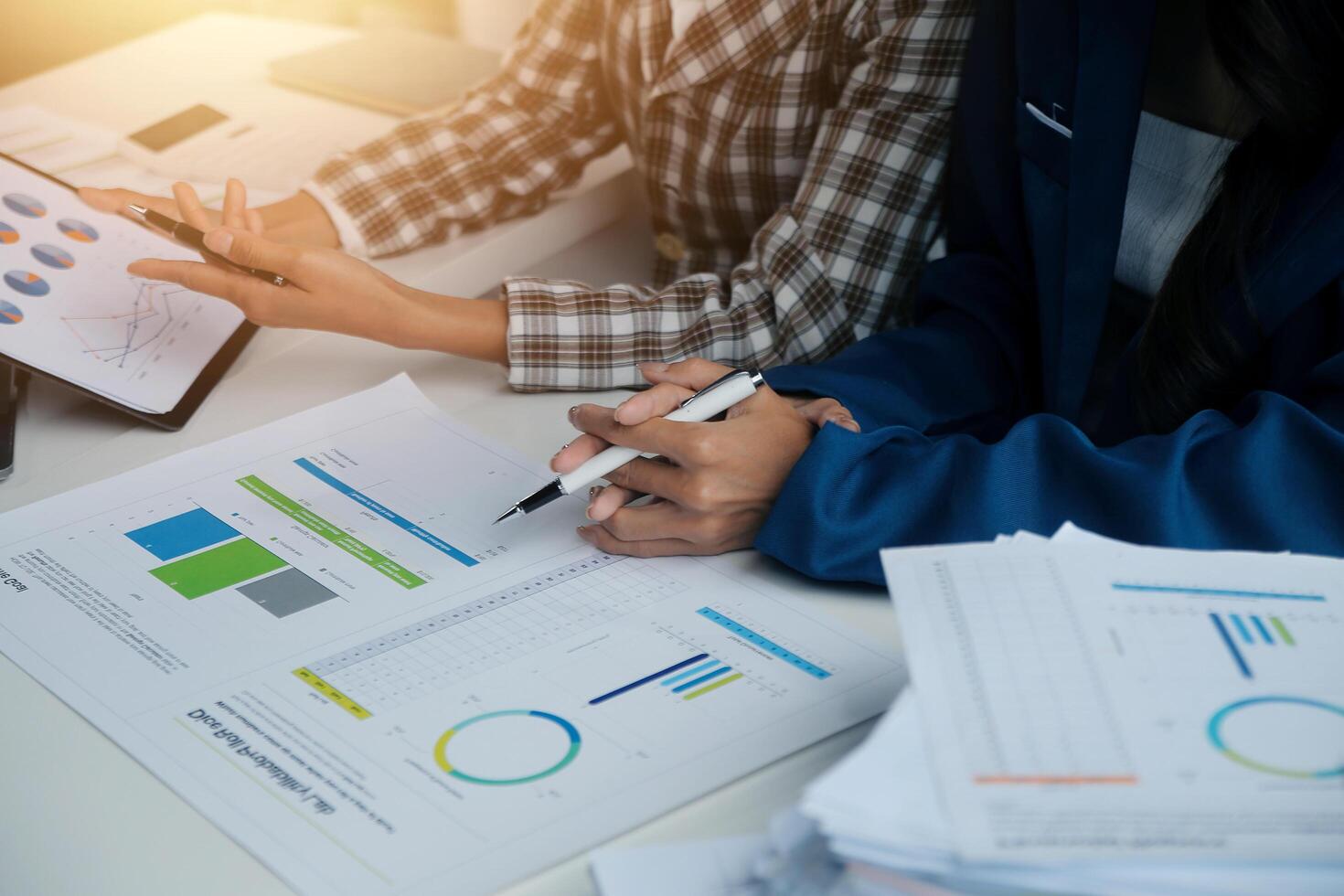 Group of confident business people point to graphs and charts to analyze market data, balance sheet, account, net profit to plan new sales strategies to increase production capacity. photo