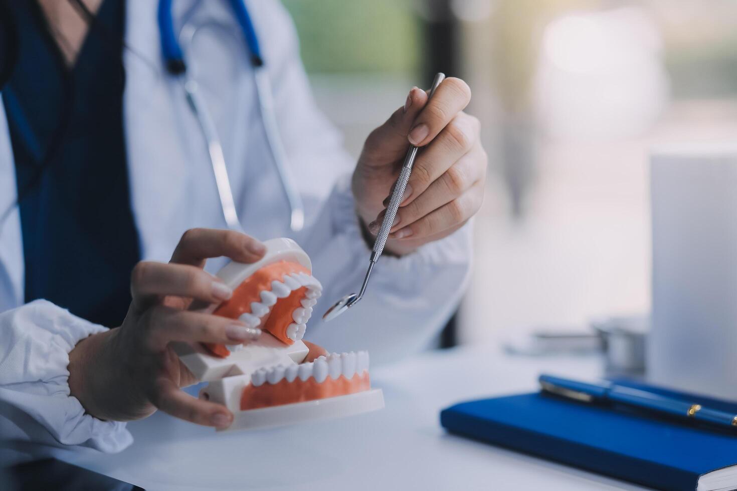 Concentrated dentist sitting at table with jaw samples tooth model and working with tablet and laptop in dental office professional dental clinic. medical doctor working photo