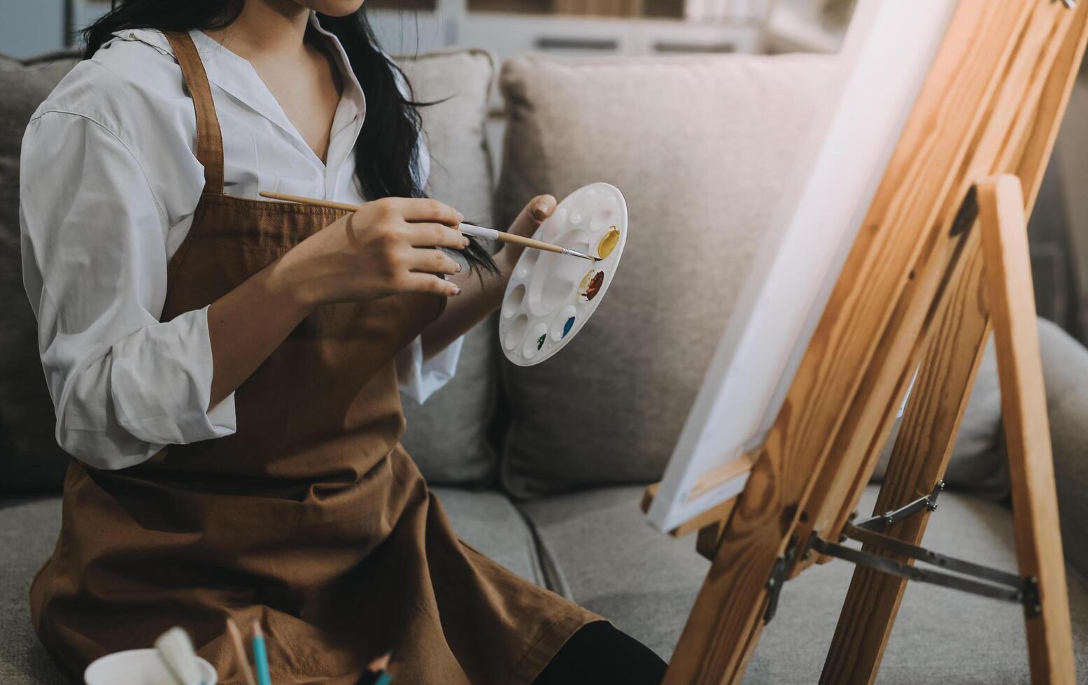 Pretty talented female painter painting on easel, making colorful sketches, creating marine landscape. Beautiful female artist painting with watercolor paints. Creativity and imagination concept photo