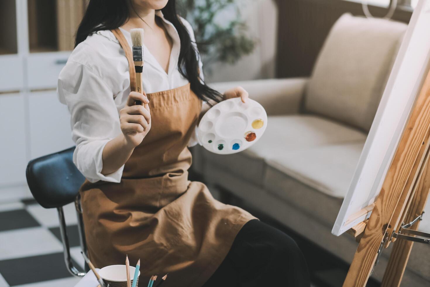 Pretty talented female painter painting on easel, making colorful sketches, creating marine landscape. Beautiful female artist painting with watercolor paints. Creativity and imagination concept photo
