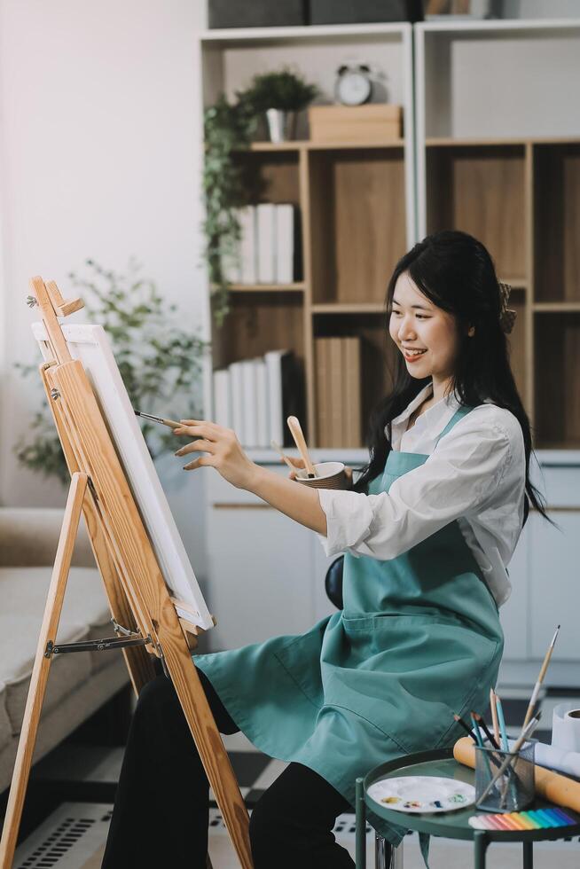 Pretty talented female painter painting on easel, making colorful sketches, creating marine landscape. Beautiful female artist painting with watercolor paints. Creativity and imagination concept photo