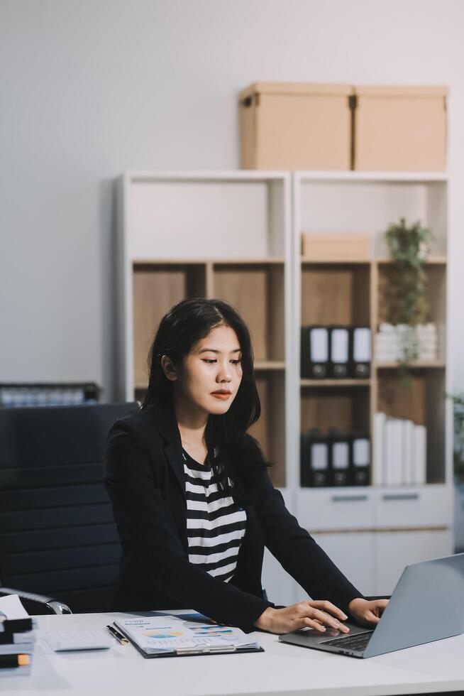 Asian business woman are delighted and happy with the work they do on their tablet, laptop and taking notes at office. photo