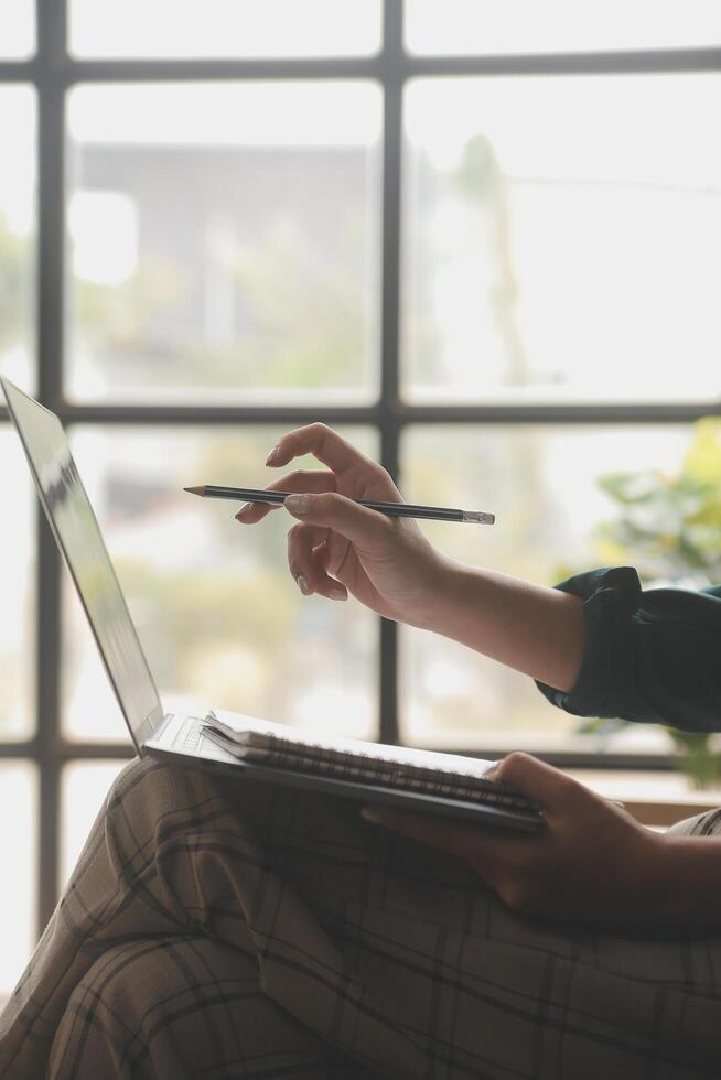 Distracted from work worried young woman sitting on couch with laptop, thinking of problems. Pensive unmotivated lady looking at window, feeling lack of energy, doing remote freelance tasks at home. photo