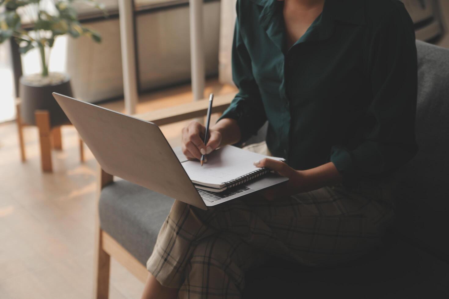 Distracted from work worried young woman sitting on couch with laptop, thinking of problems. Pensive unmotivated lady looking at window, feeling lack of energy, doing remote freelance tasks at home. photo
