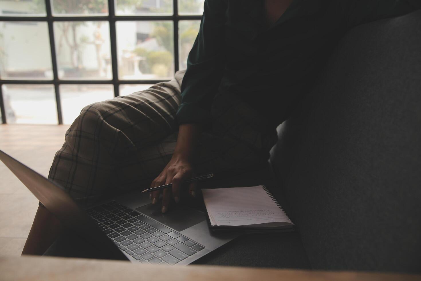 Distracted from work worried young woman sitting on couch with laptop, thinking of problems. Pensive unmotivated lady looking at window, feeling lack of energy, doing remote freelance tasks at home. photo
