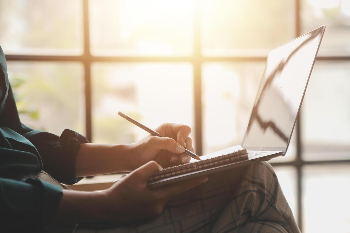 Distracted from work worried young woman sitting on couch with laptop, thinking of problems. Pensive unmotivated lady looking at window, feeling lack of energy, doing remote freelance tasks at home. photo