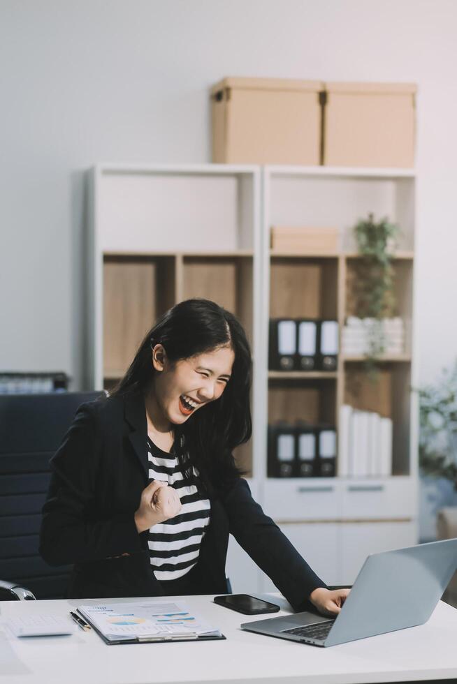 Asian business woman are delighted and happy with the work they do on their tablet, laptop and taking notes at office. photo