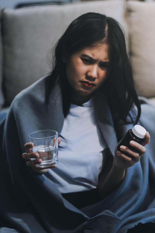 Cold medicine and sick woman drinking hot beverage to get well from flu, fever and virus. Dirty paper towels and tissues on table. Ill person wearing warm woolen stocking socks in winter. photo