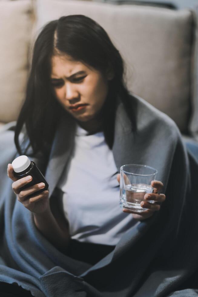 Cold medicine and sick woman drinking hot beverage to get well from flu, fever and virus. Dirty paper towels and tissues on table. Ill person wearing warm woolen stocking socks in winter. photo