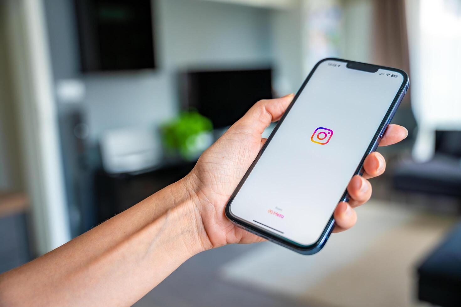 Prague, Czech republic - May 2, 2024. Woman holding iPhone with streaming photo and Instagram on the screen, using mobile application at home. High quality photo