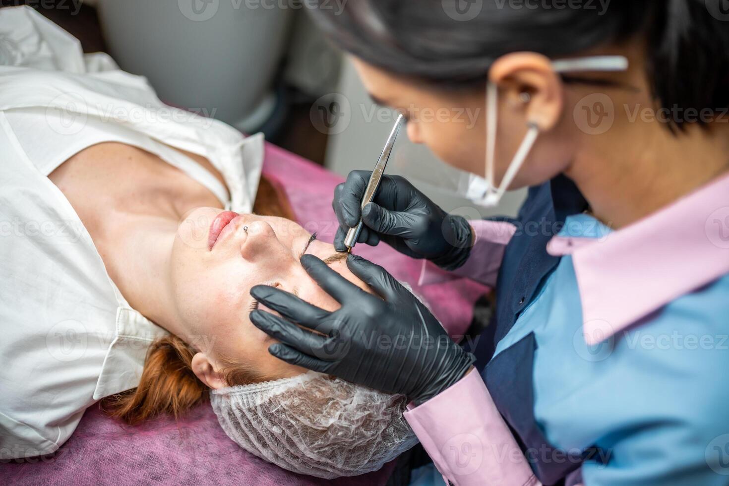 Procedure of eyebrow microblading. A master in black gloves is doing a blending needle of model's brow. High quality photo