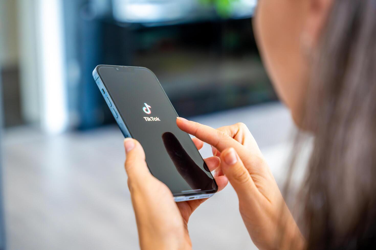 Prague, Czech republic - May 2, 2024. Woman holding iPhone with streaming service media and TikTok on the screen, using mobile application at home. High quality photo