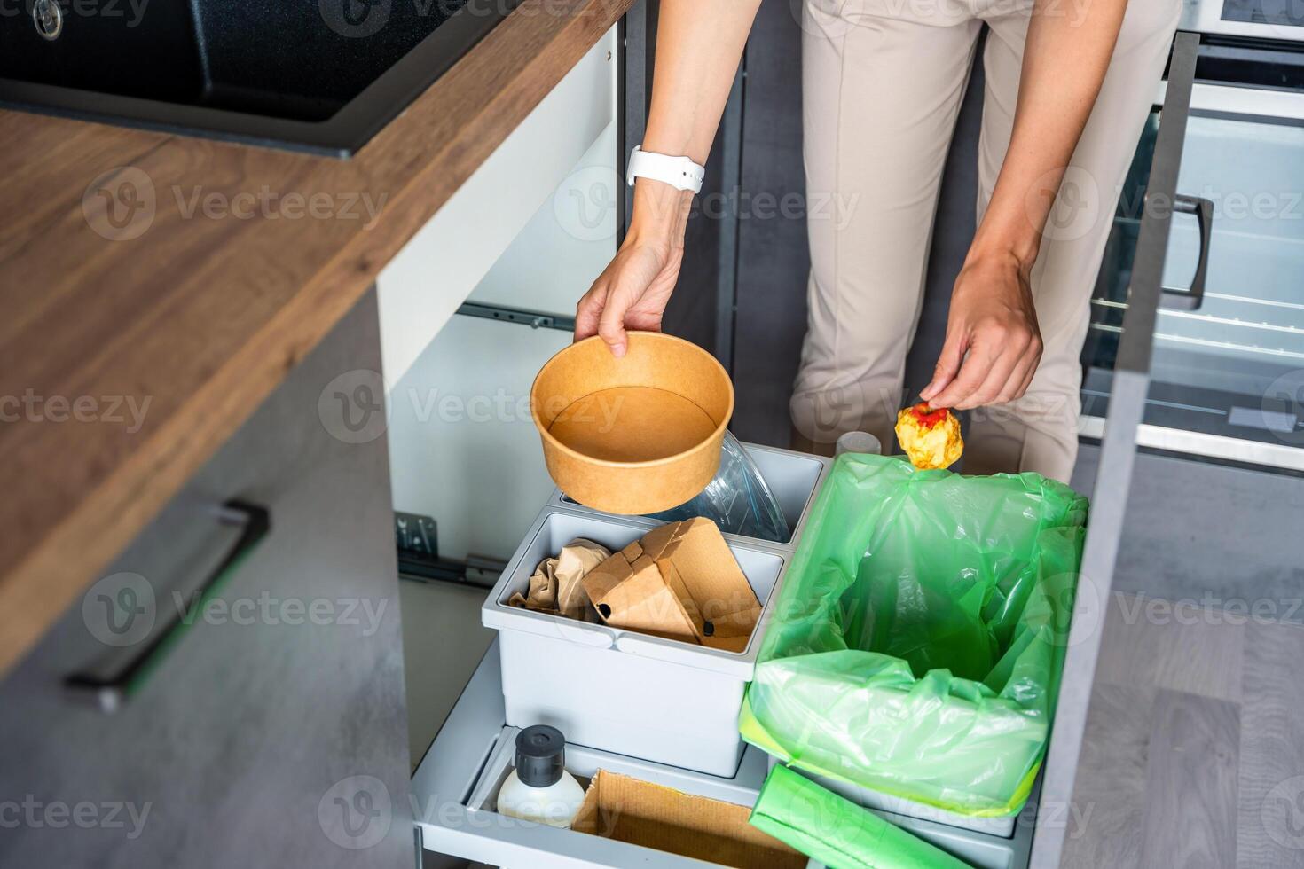 Woman throwing trash into household bins for waste sorting in the kitchen for recycle. Plastic, paper, bio and mixed waste. Sorting waste at home concept. High quality photo