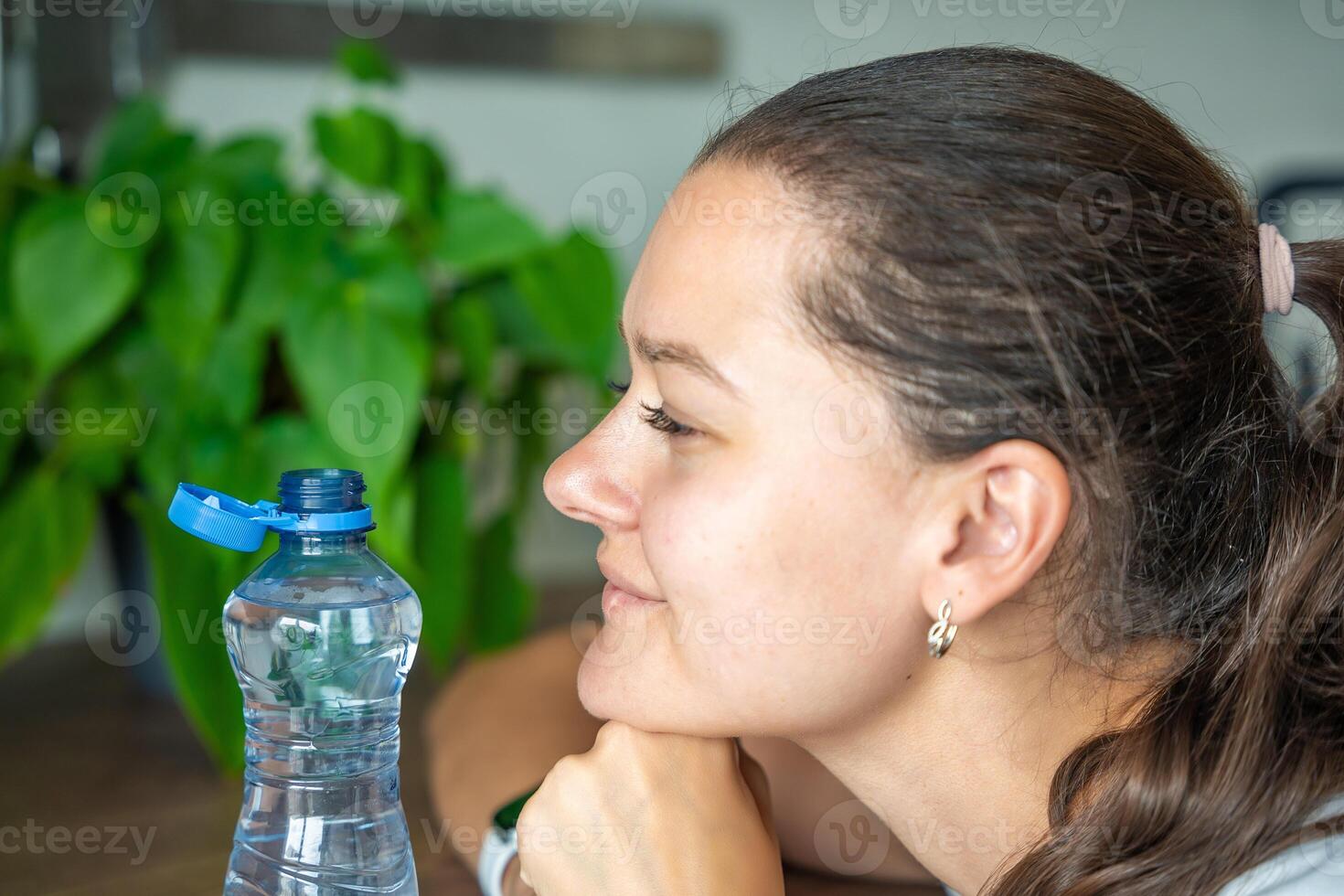 Young woman with bottle with stationary plastic cap. The new design means the cap remains attached to the bottle after opening, making the entire package easier to collect and recycle. photo