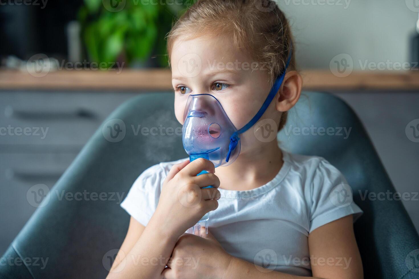Cute little girl are sitting and holding a nebulizer mask leaning against the face, airway treatment concept photo