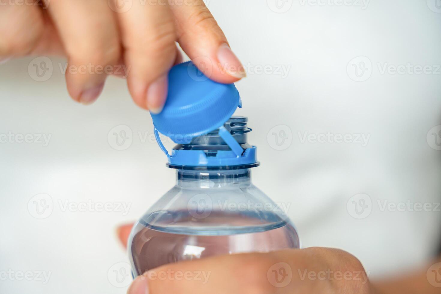Bottle with stationary plastic cap in woman hand. The new design means the cap remains attached to the bottle after opening, making the entire package easier to collect and recycle. High quality photo
