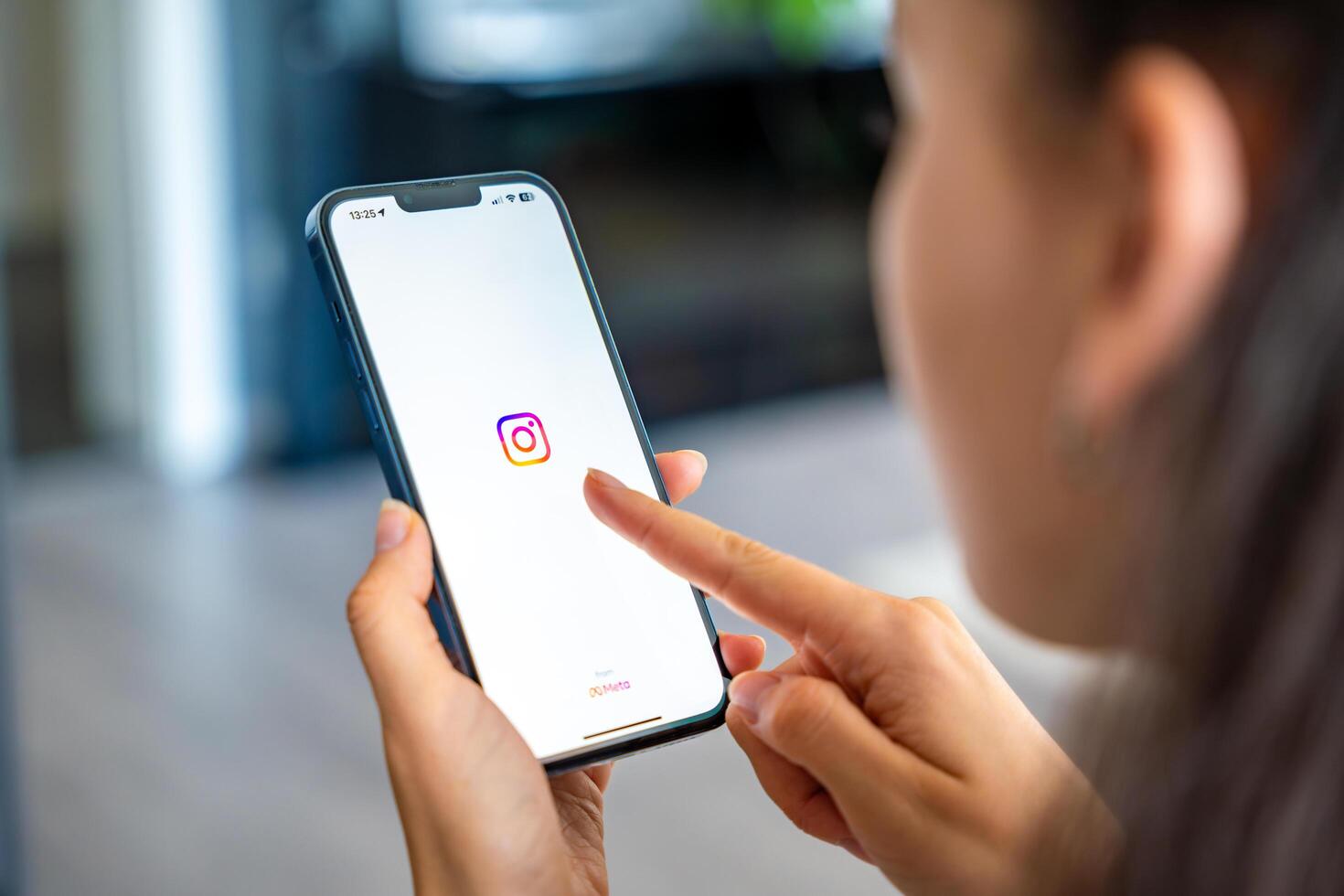 Prague, Czech republic - May 2, 2024. Woman holding iPhone with streaming photo and Instagram on the screen, using mobile application at home. High quality photo