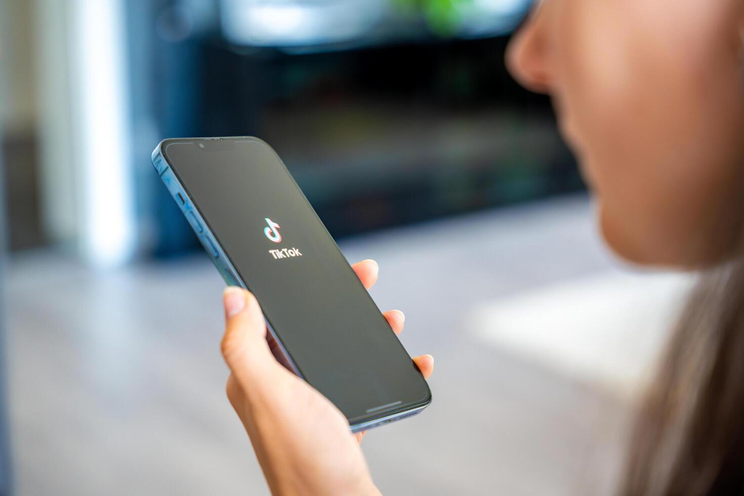 Prague, Czech republic - May 2, 2024. Woman holding iPhone with streaming service media and TikTok on the screen, using mobile application at home. High quality photo