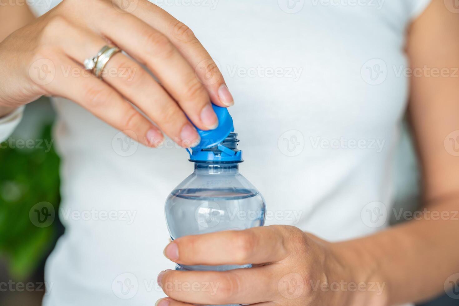 Bottle with stationary plastic cap in woman hand. The new design means the cap remains attached to the bottle after opening, making the entire package easier to collect and recycle. High quality photo