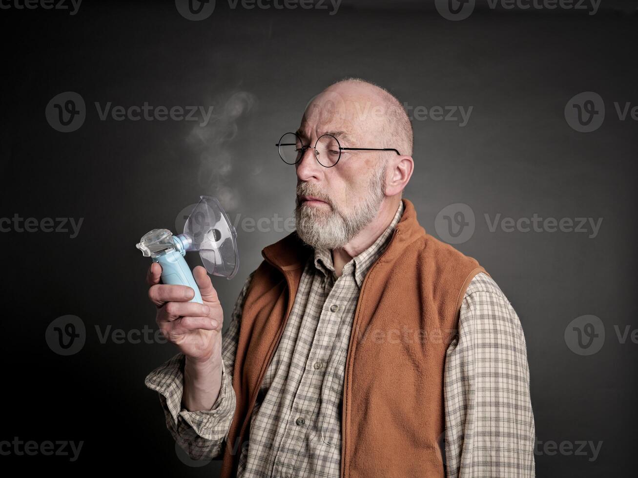 senior man using a portable handheld nebulizer photo