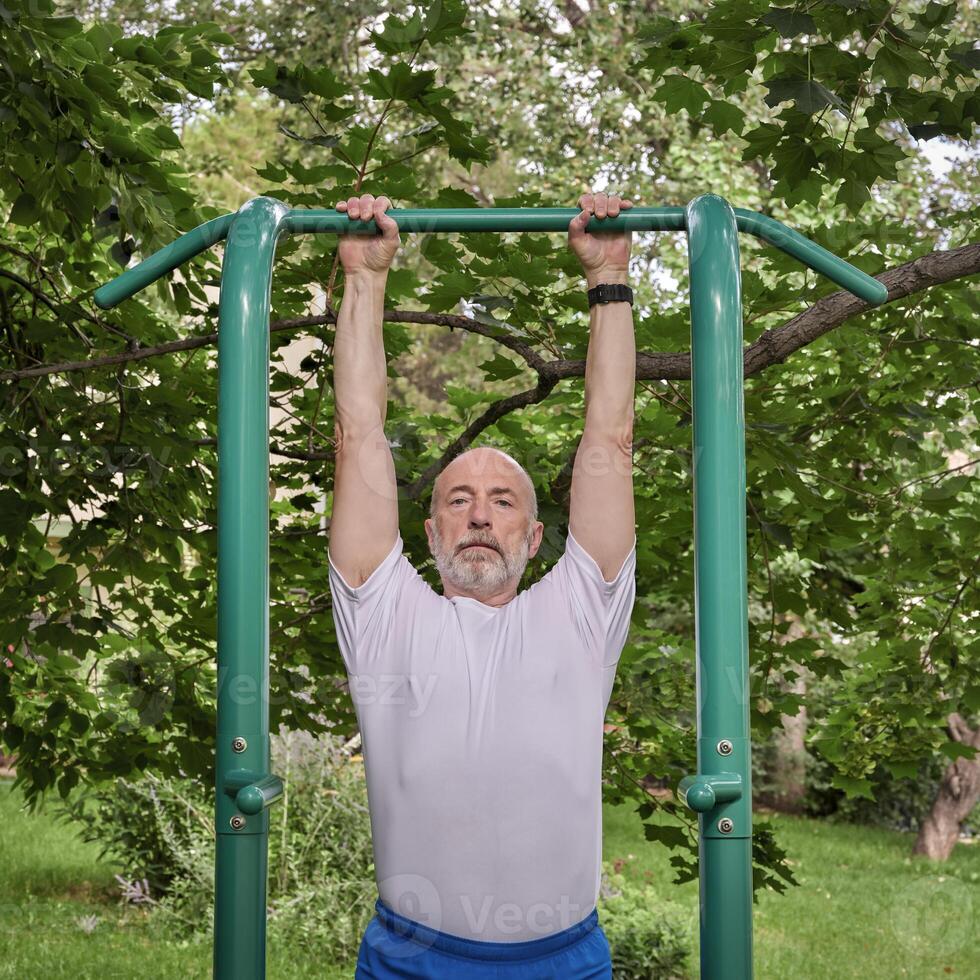 senior male exercising on outdoor fitness tower photo