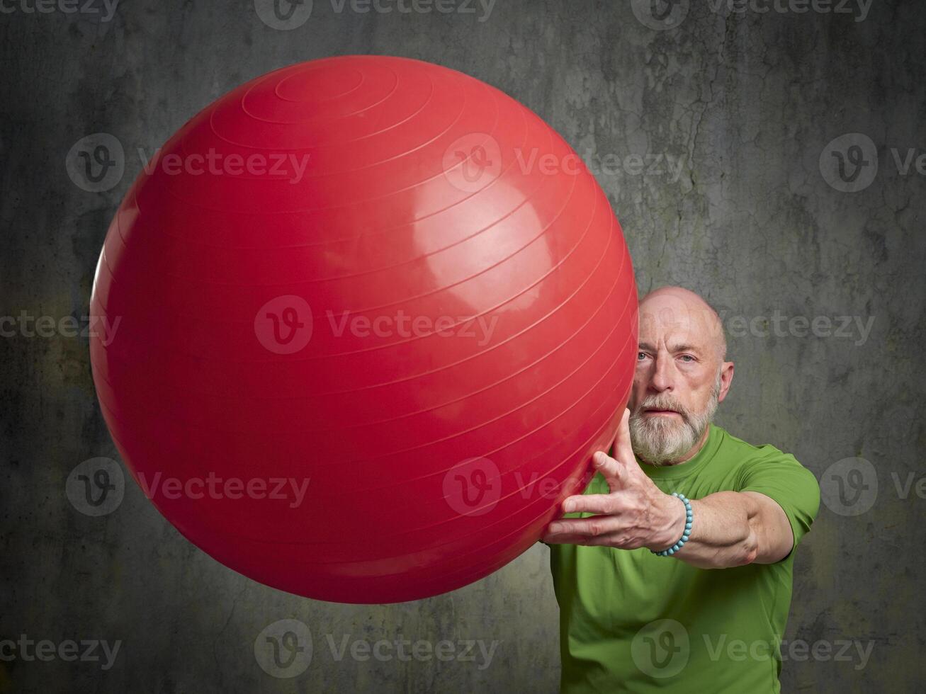 senior man exercising with a large Swiss ball photo