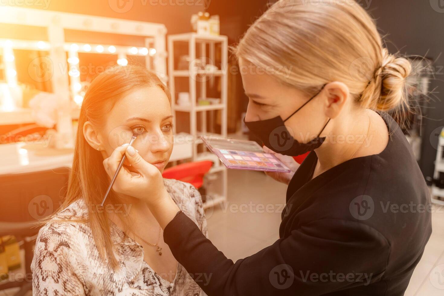 Make-up artist working with brush on model eyes Close up of applying make up on young girl,semi profile, professional make up in beauty studio photo