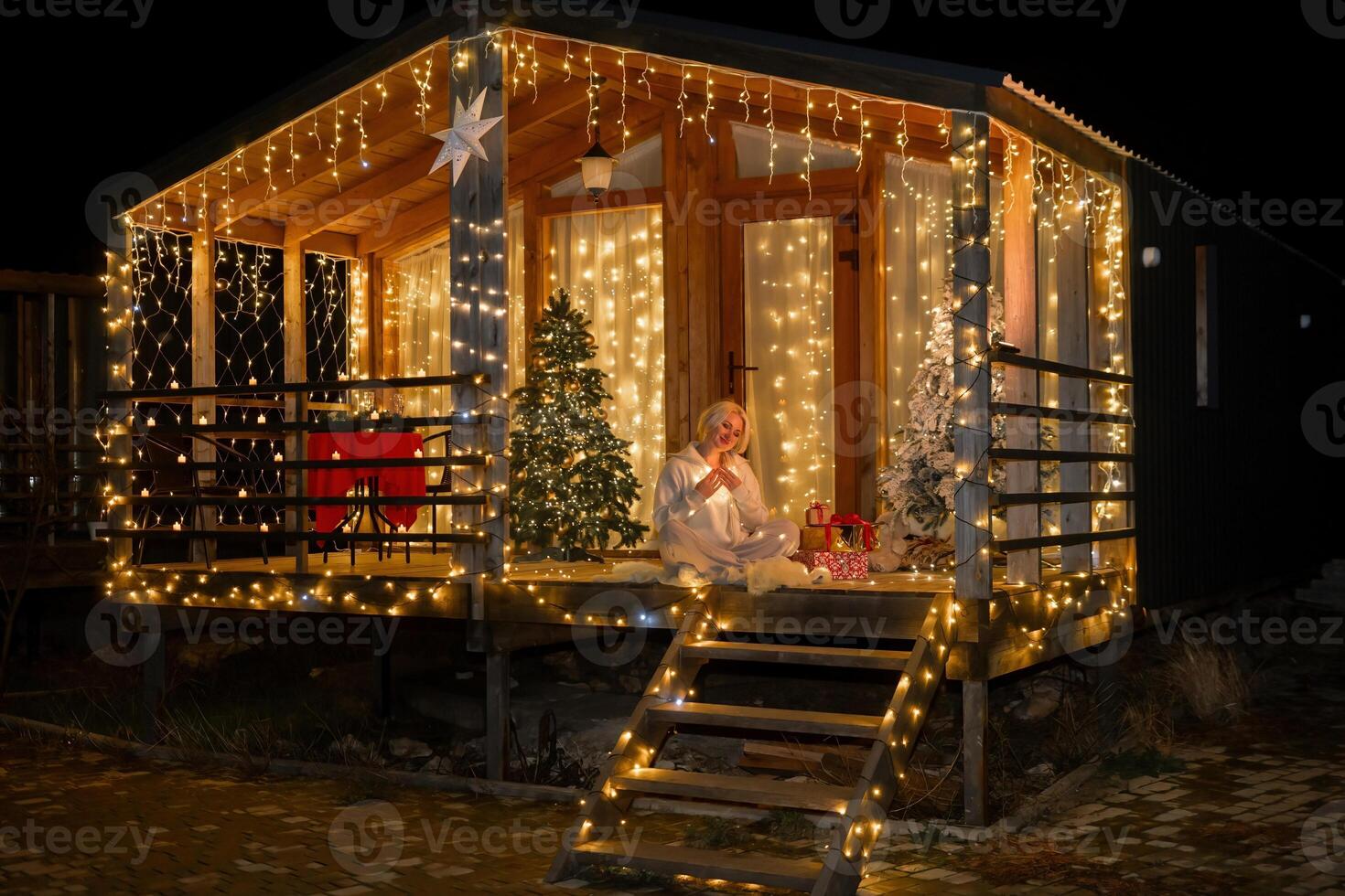 Woman by Christmas tree. Festive setting. Illustrating holiday cheer and celebration. She is posing for a picture, and there are presents nearby, adding to the festive atmosphere. photo