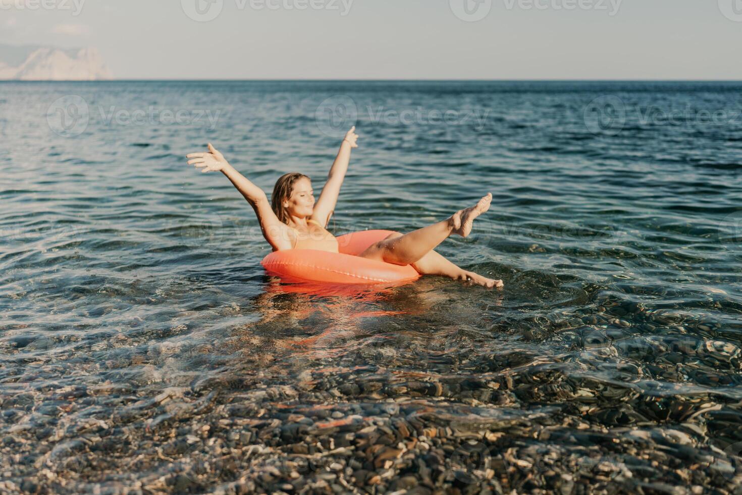A woman is floating in a red inflatable tube in the ocean photo