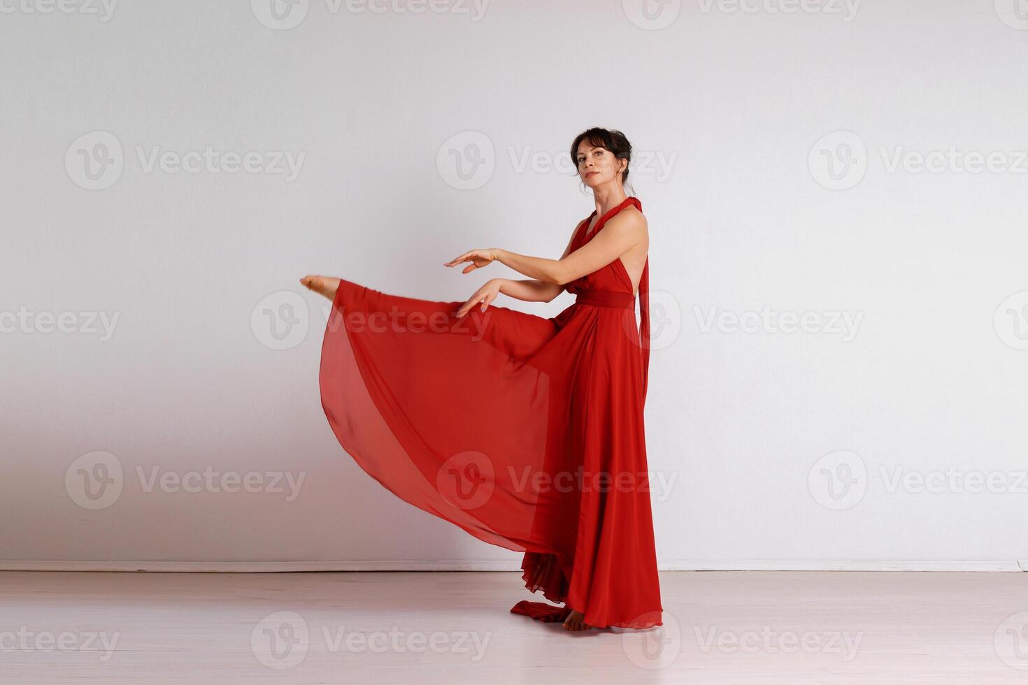Dancer in a red flying dress. Woman ballerina dancing on a white studio background photo