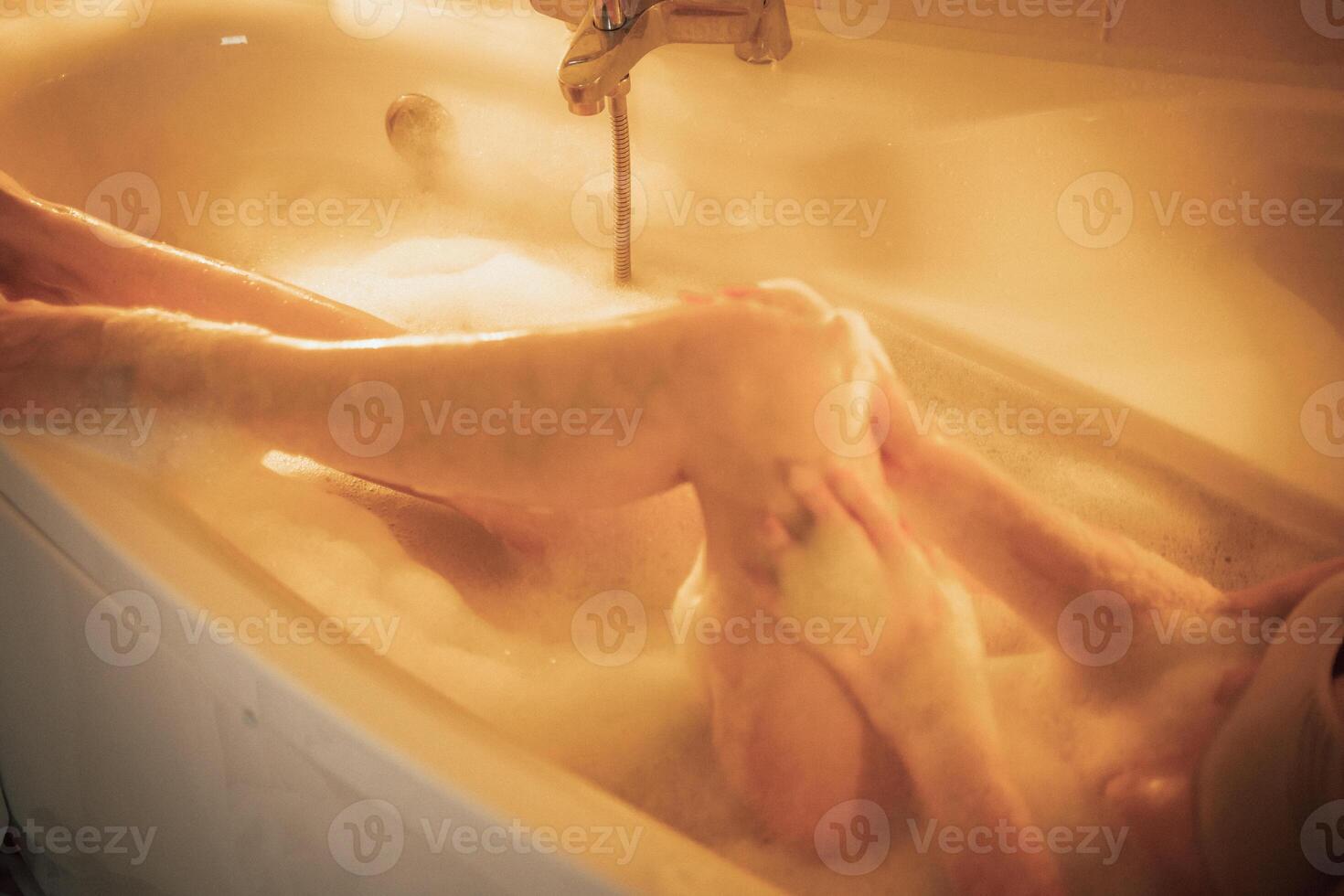 Women's feet in bath foam. View from above. Enjoy and relax in a spa hotel photo