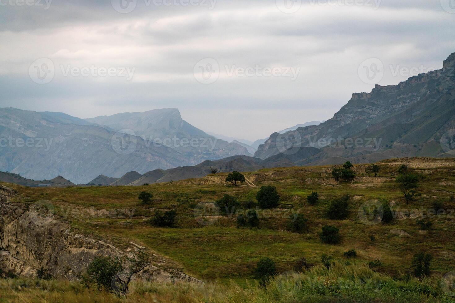 A mountain range with a cloudy sky in the background. The sky is overcast and the mountains are covered in trees. photo