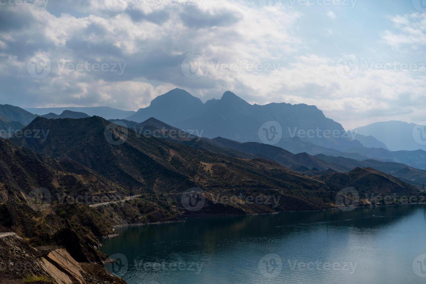 The mountains are covered in trees and the sky is cloudy. The water is calm and the mountains are in the background. photo
