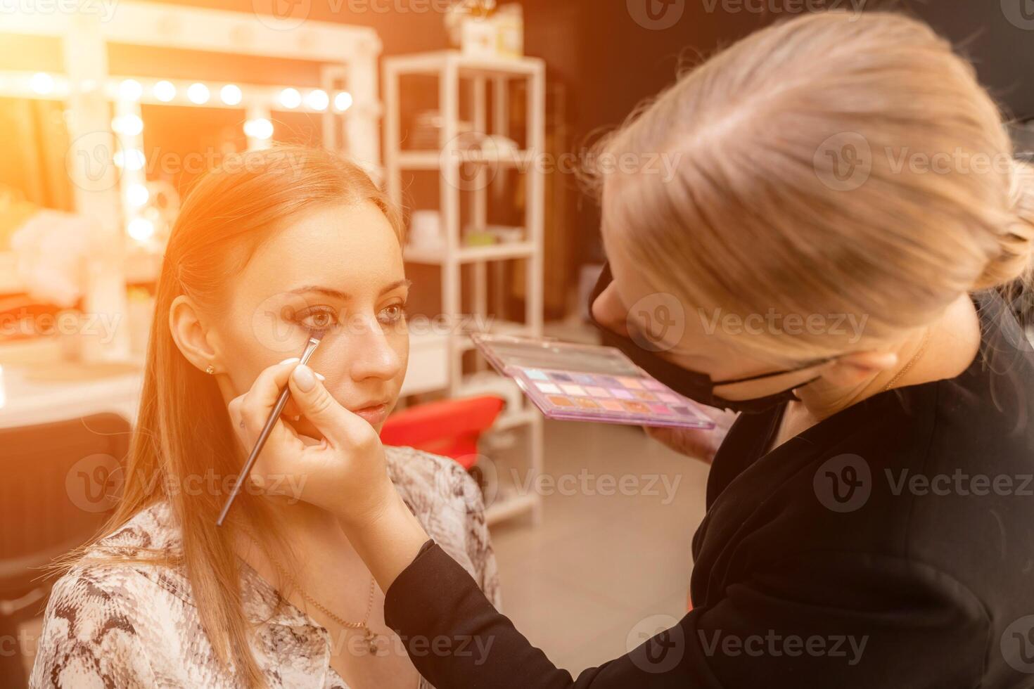 Make-up artist working with brush on model eyes Close up of applying make up on young girl,semi profile, professional make up in beauty studio photo