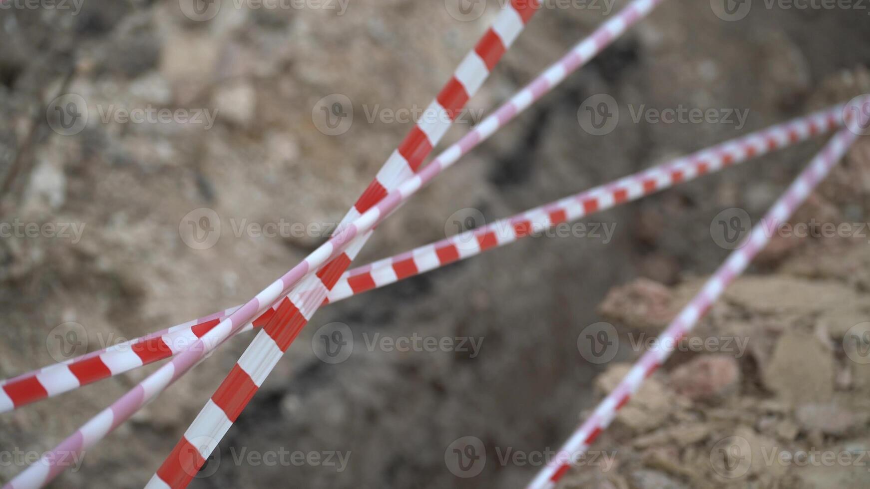 Red white barrier tape trenches. Focus on red and white barrier tape at construction site. Ribbons indicate dug trenches. photo