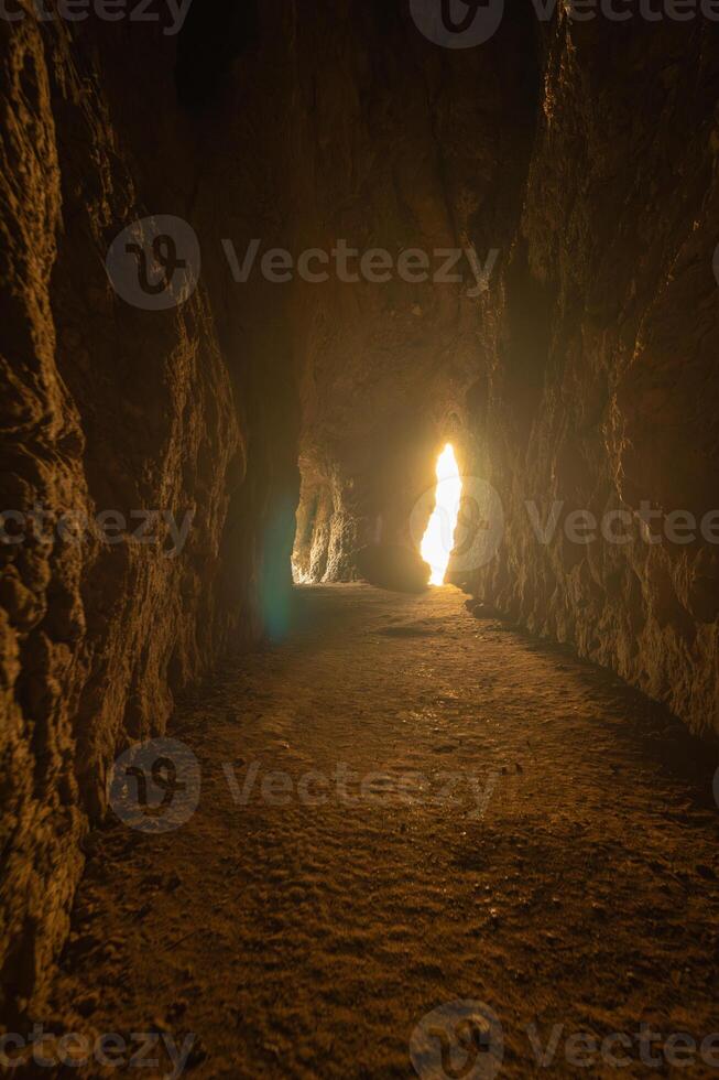 A cave with a small opening in the wall. The light shining through the opening creates a warm and inviting atmosphere. photo