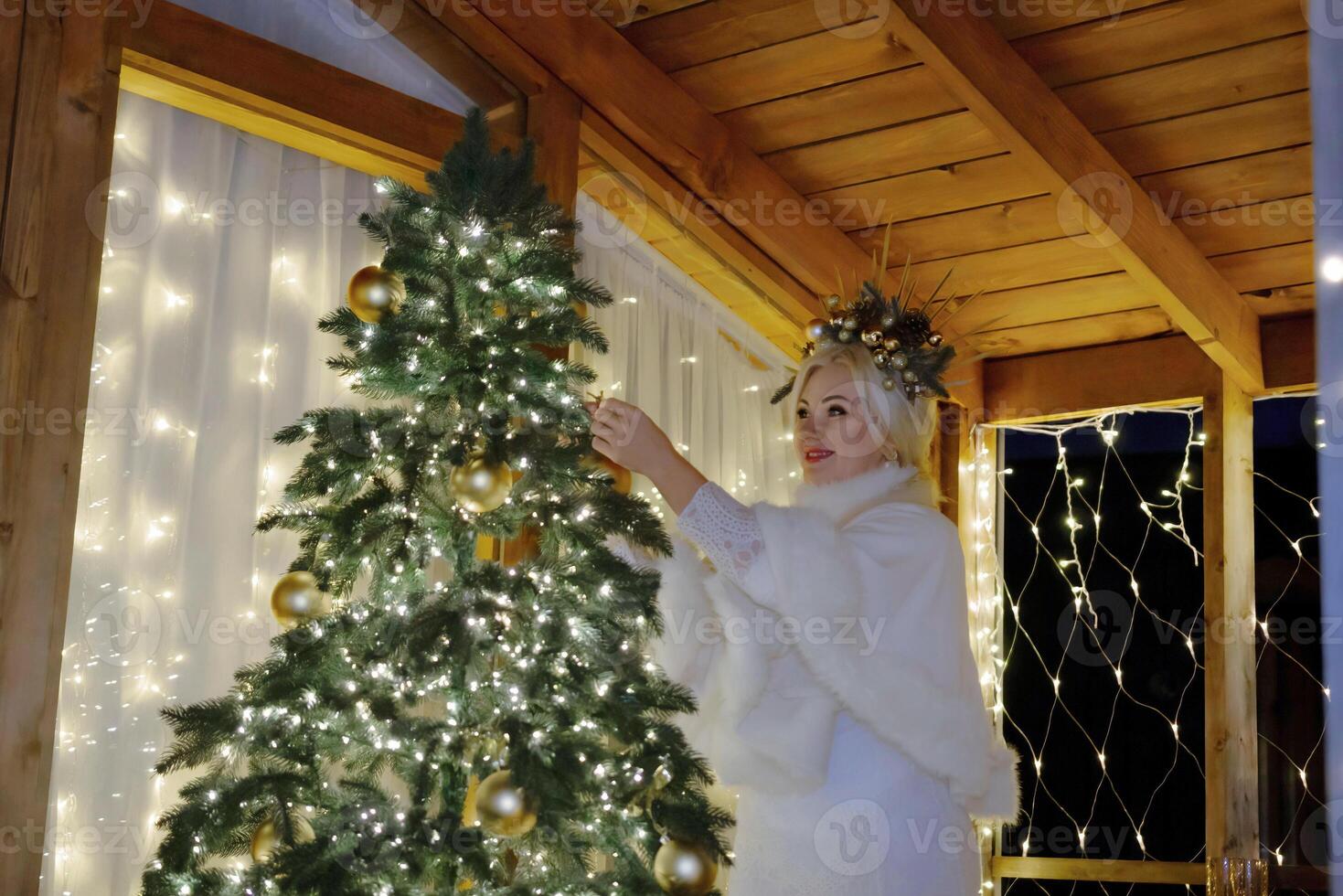 Woman by Christmas tree. Festive setting. Illustrating holiday cheer and celebration. She is posing for a picture, and there are presents nearby, adding to the festive atmosphere. photo