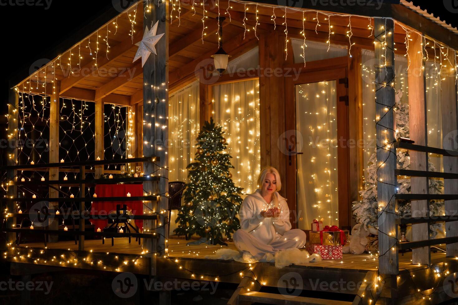 Woman by Christmas tree. Festive setting. Illustrating holiday cheer and celebration. She is posing for a picture, and there are presents nearby, adding to the festive atmosphere. photo