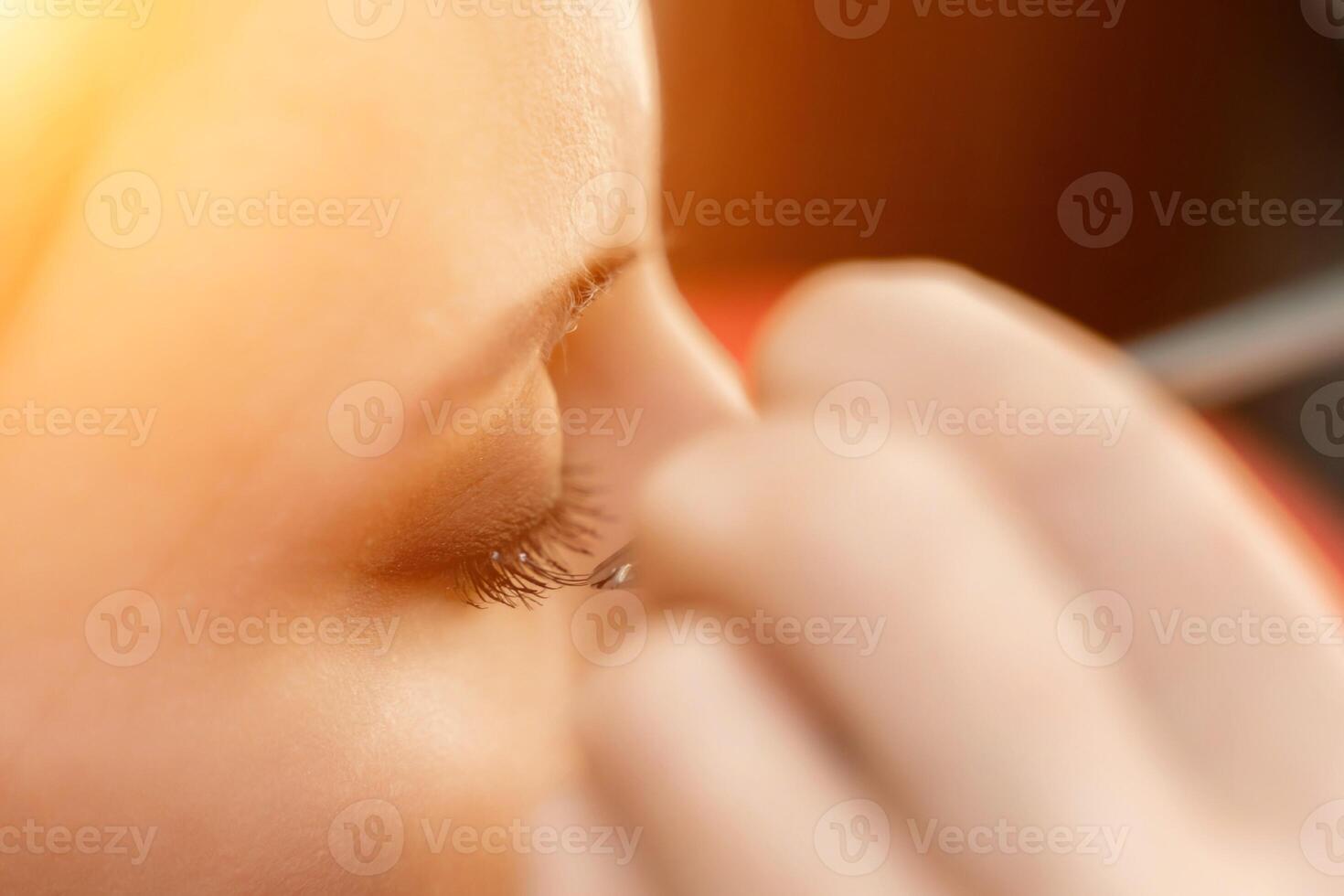 Makeup artist paints eyelashes to a woman in a beauty salon. photo