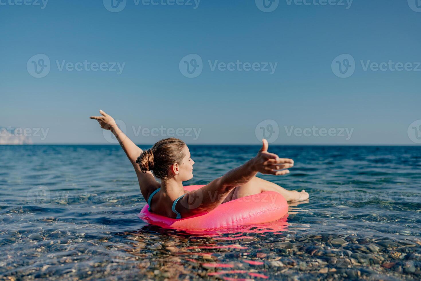 A woman is floating on a pink inflatable raft in the ocean photo