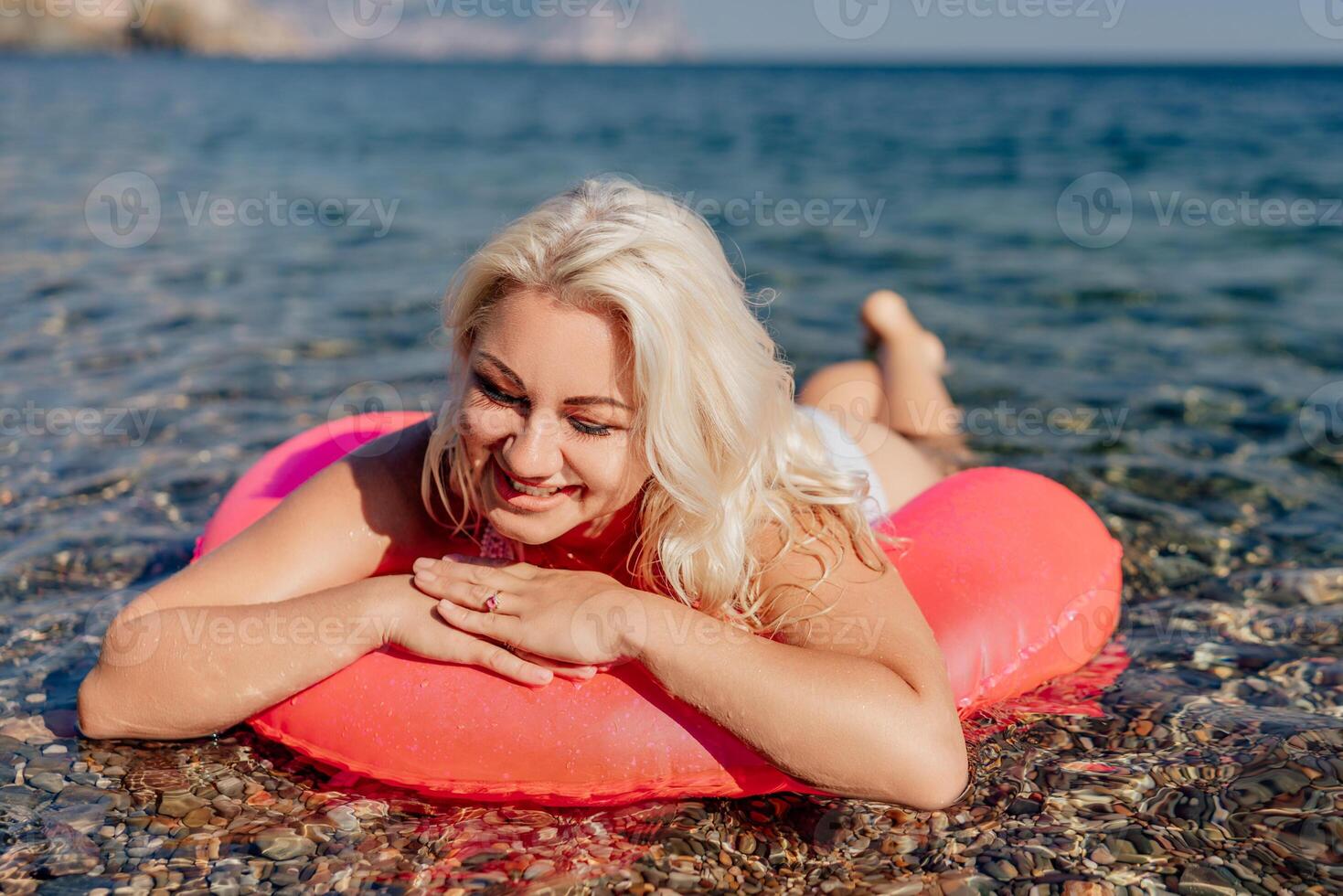 A woman is laying on a red inflatable raft in the ocean photo